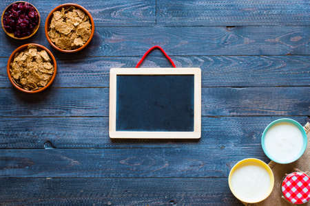Bowl of fresh fruit with banana, apple, strawberries, apricots, blueberries, plums, whole grains, forks, spoon, free space for text. top viewの写真素材