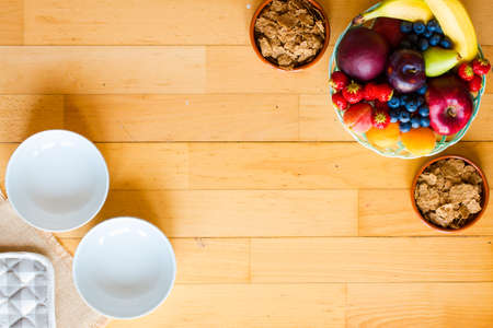 Bowl of fresh fruit with banana, apple, strawberries, apricots, blueberries, plums, whole grains, forks, spoon, free space for text. top viewの写真素材