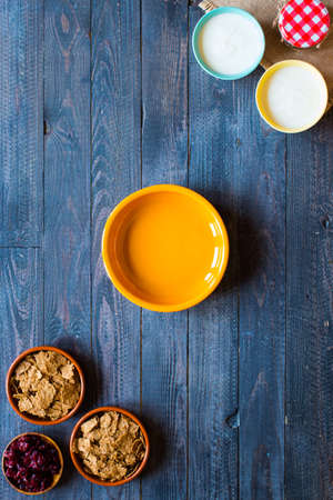 Bowl of fresh fruit with banana, apple, strawberries, apricots, blueberries, plums, whole grains, forks, spoon, free space for text. top viewの写真素材