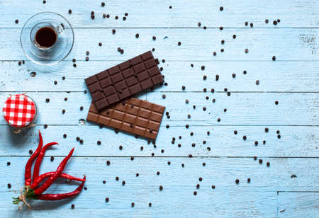 Dark chocolate and milk chocolate, with red hot chili peppers, on a wooden background, free space for textの写真素材