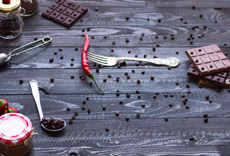 Dark chocolate and milk chocolate, with red hot chili peppers, on a wooden background, free space for textの写真素材
