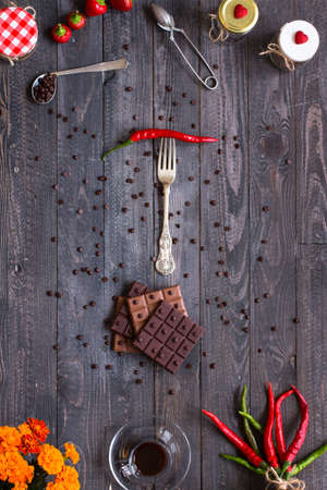 Dark chocolate and milk chocolate, with red hot chili peppers, on a wooden background, free space for textの写真素材