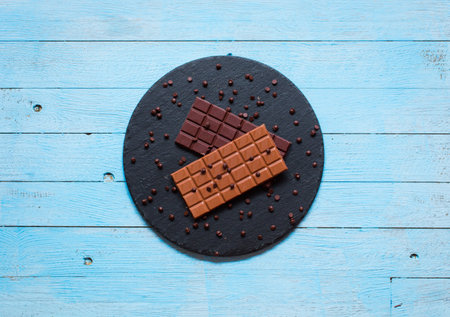 Dark chocolate and milk chocolate, with red hot chili peppers, on a wooden background, free space...