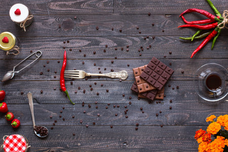 Dark chocolate and milk chocolate, with red hot chili peppers, on a wooden background, free space...