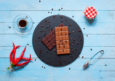Dark chocolate and milk chocolate, with red hot chili peppers, on a wooden background, free space for textの写真素材