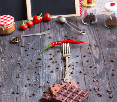 Dark chocolate and milk chocolate, with red hot chili peppers, on a wooden background, free space for textの写真素材