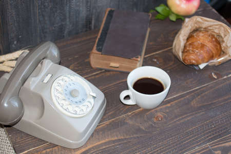 Old vintage telephone, coffee, book, on a wooden background, free space for text.の写真素材