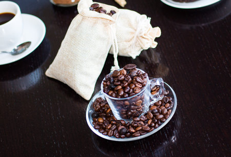 Coffee beans and cup of coffee with other components on different wooden background. Free space for...