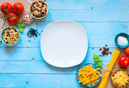 Different types of pasta with various types of vegetables, health or vegetarian concept on a wooden background, free space for text. Top viewの写真素材