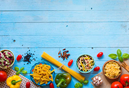 Different types of pasta with various types of vegetables, health or vegetarian concept on a wooden background, free space for text. Top viewの写真素材