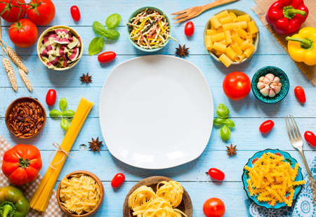 Different types of pasta with various types of vegetables, health or vegetarian concept on a wooden background, free space for text. Top viewの写真素材