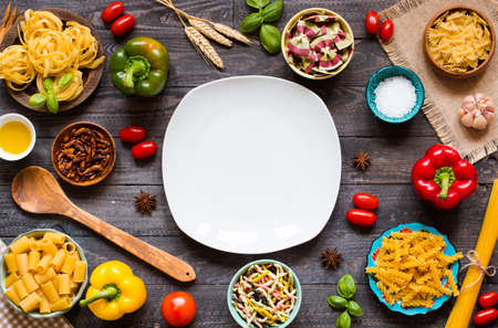 Different types of pasta with various types of vegetables, health or vegetarian concept on a wooden background, free space for text. Top viewの写真素材