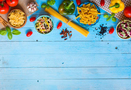 Different types of pasta with various types of vegetables, health or vegetarian concept on a wooden background, free space for text. Top viewの写真素材
