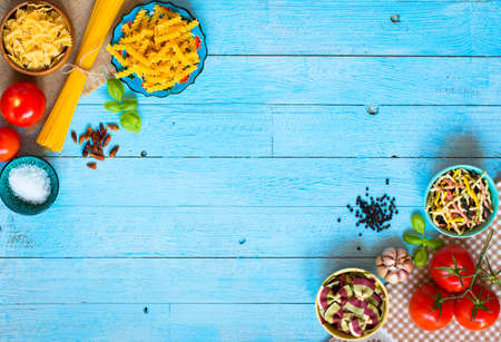 Different types of pasta with various types of vegetables, health or vegetarian concept on a wooden background, free space for text. Top viewの写真素材