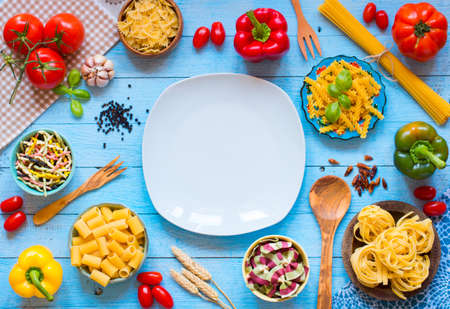 Different types of pasta with various types of vegetables, health or vegetarian concept on a wooden background, free space for text. Top viewの写真素材