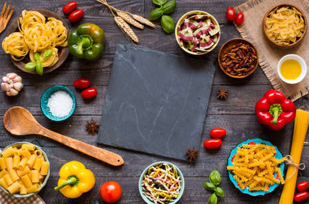 Different types of pasta with various types of vegetables, health or vegetarian concept on a wooden background, free space for text. Top viewの写真素材