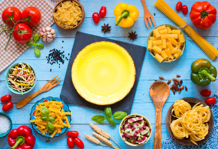 Different types of pasta with various types of vegetables, health or vegetarian concept on a wooden background, free space for text. Top viewの写真素材