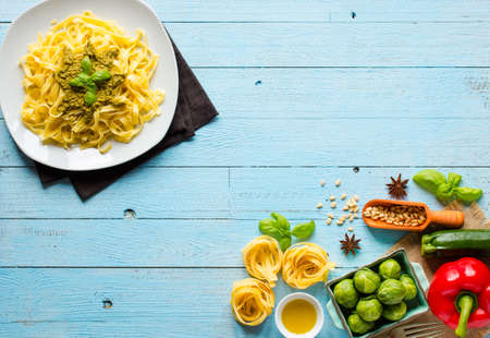Pasta tagliatelle with pesto sauce and other vegetables on a wood background, free space for text. Top viewの写真素材