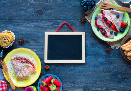 Fresh homemade crepes served on a plate with strawberries and blueberries, on a dark wooden background, free space for text.の写真素材