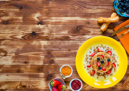 Homemade pancakes with fresh berries, strawberries, blueberries and maple syrup on a wooden background. Free space for textの写真素材