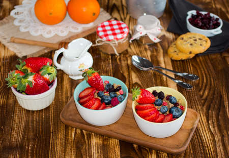 Cereal. Breakfast with muesli, and fresh fruits in bowls on a rustic wooden background, free space for textの写真素材
