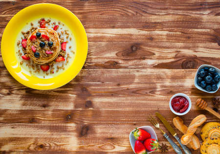 Homemade pancakes with fresh berries, strawberries, blueberries and maple syrup on a wooden background. Free space for textの写真素材