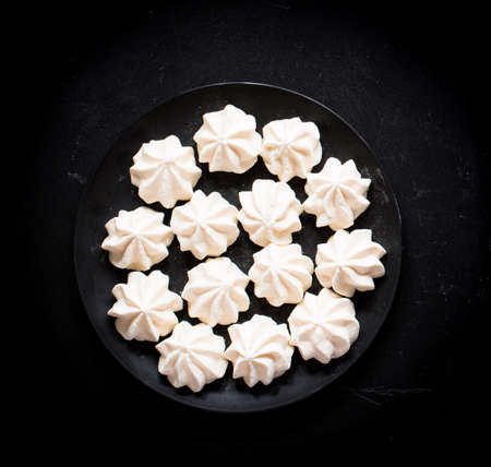 Sweet white meringue on a black wooden background, free space for text. Top viewの写真素材