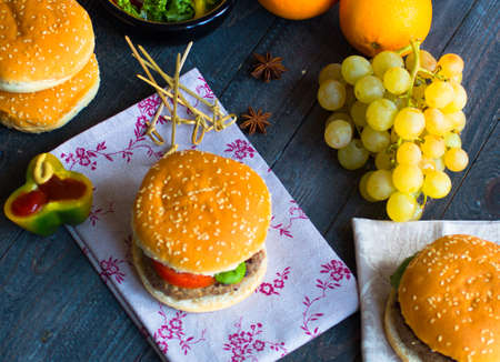 Homemade burger with vegetables, spices and beef meat on a wooden backgroundの写真素材