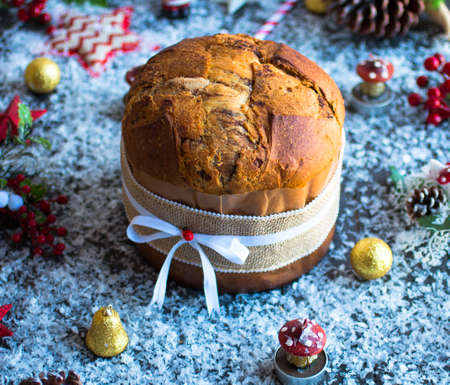 Italian chocolate panettone Christmas cake with bauble decorations, candles,pine cones, on a wooden background. Free space for textの写真素材