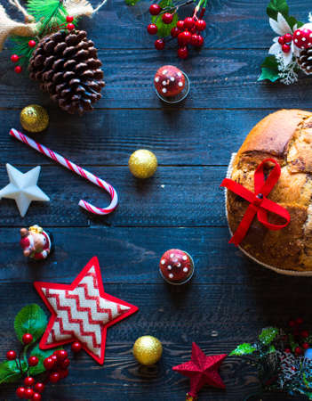 Italian chocolate panettone Christmas cake with bauble decorations, candles,pine cones, on a wooden background. Free space for textの写真素材