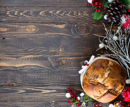 Italian chocolate panettone Christmas cake with bauble decorations, candles,pine cones, on a wooden background. Free space for textの写真素材