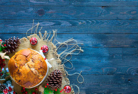 Italian chocolate panettone Christmas cake with bauble decorations, candles,pine cones, on a wooden background. Free space for textの写真素材