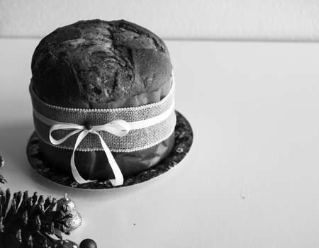 Italian chocolate panettone Christmas cake with bauble decorations, candles,pine cones, on a wooden background. Free space for textの写真素材