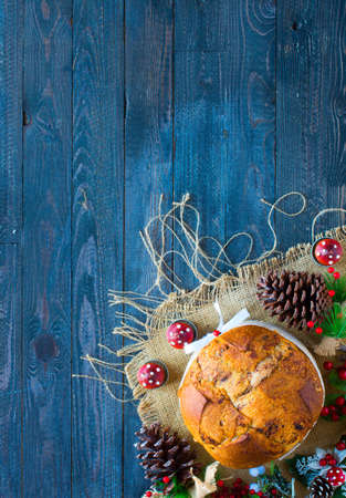 Italian chocolate panettone Christmas cake with bauble decorations, candles,pine cones, on a wooden background. Free space for textの写真素材