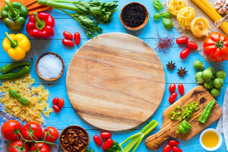 Top view of a wooden table full of italian pasta ingradients like peppers, tomatoes, olive oil, basil,  garlic and several spices.の写真素材