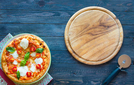Top view of italian classic pizza margherita over a wooden table with toppings like tomatoes, basil, oregano.の写真素材