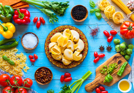 Top view of a wooden table full of italian pasta ingradients like peppers, tomatoes, olive oil, basil,  garlic and several spices.の写真素材
