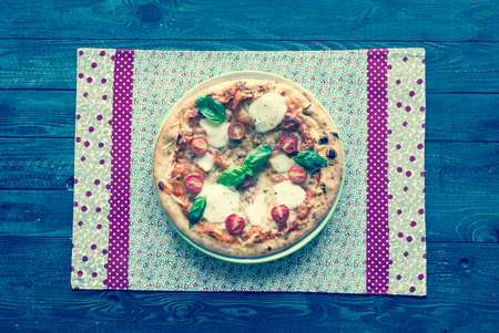 Top view of italian classic pizza margherita over a wooden table with toppings like tomatoes, basil, oregano.の写真素材