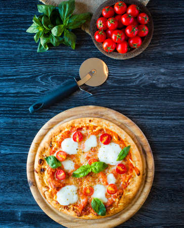 Top view of italian classic pizza margherita over a wooden table with toppings like tomatoes, basil, oregano.の写真素材
