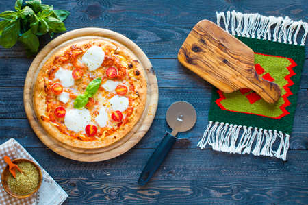 Top view of italian classic pizza margherita over a wooden table with toppings like tomatoes, basil, oregano.の写真素材