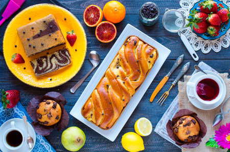 Breakfast with coffee and tea with different pastries and fruits on a wooden table free space for textの写真素材