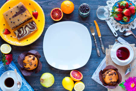 Breakfast with coffee and tea with different pastries and fruits on a wooden table free space for textの写真素材