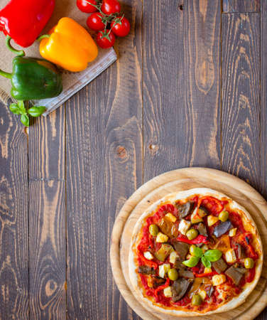 Fresh homemade pizza with different vegetables on a wooden background free space for textの写真素材