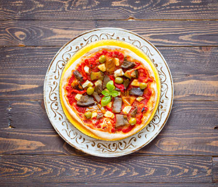 Fresh homemade pizza with different vegetables on a wooden background free space for textの写真素材
