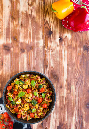 Italian pasta farfalle in tomato sauce and various type of vegetables on a wooden background, free space for text. Top viewの写真素材