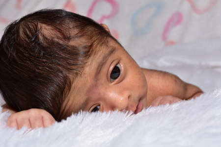 adorable smiling newborn baby. Newborn child relaxing in bedの写真素材