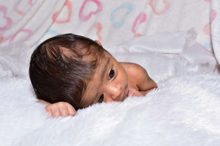 adorable smiling newborn baby. Newborn child relaxing in bedの写真素材