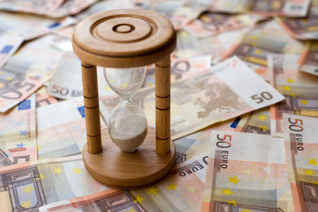 Concept or conceptual euro paper money banknote with a sand glass or time background