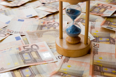 Concept or conceptual euro paper money banknote with a sand glass or time background