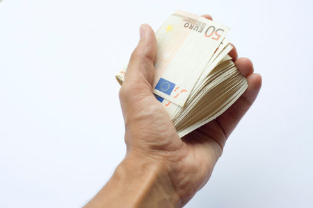 Concept or conceptual euro paper money banknote in human or man hands isolated on white background